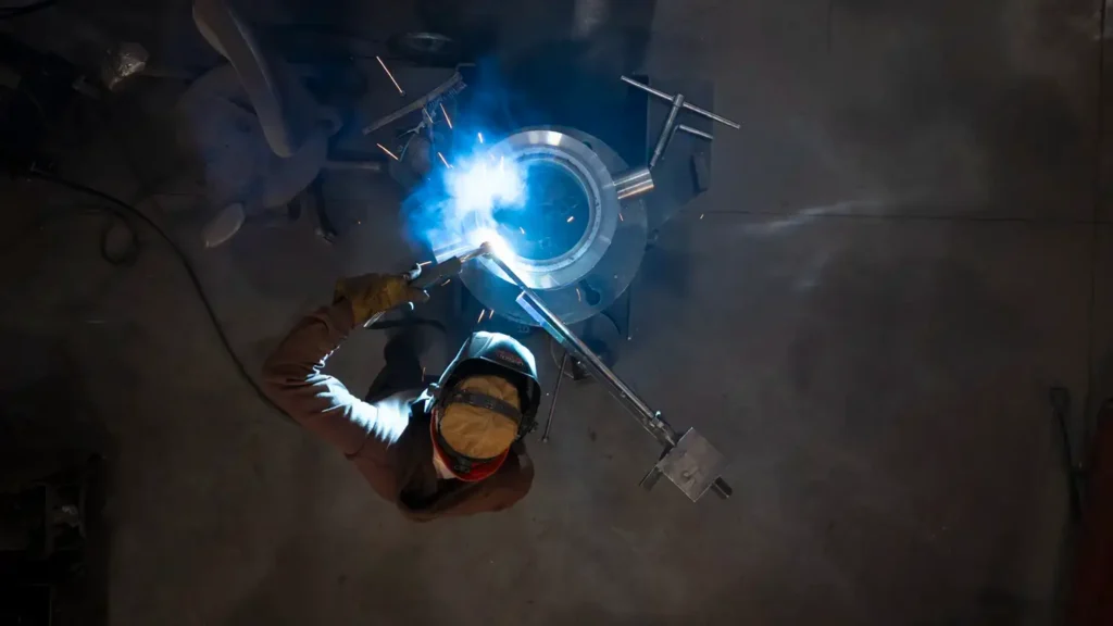 Top down view of a man welding repairing a cylinder